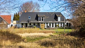 A two-story house with a dark roof, a covered porch, and a fenced yard. - 2 bedroom nice apartment in Sydals (Sydals)