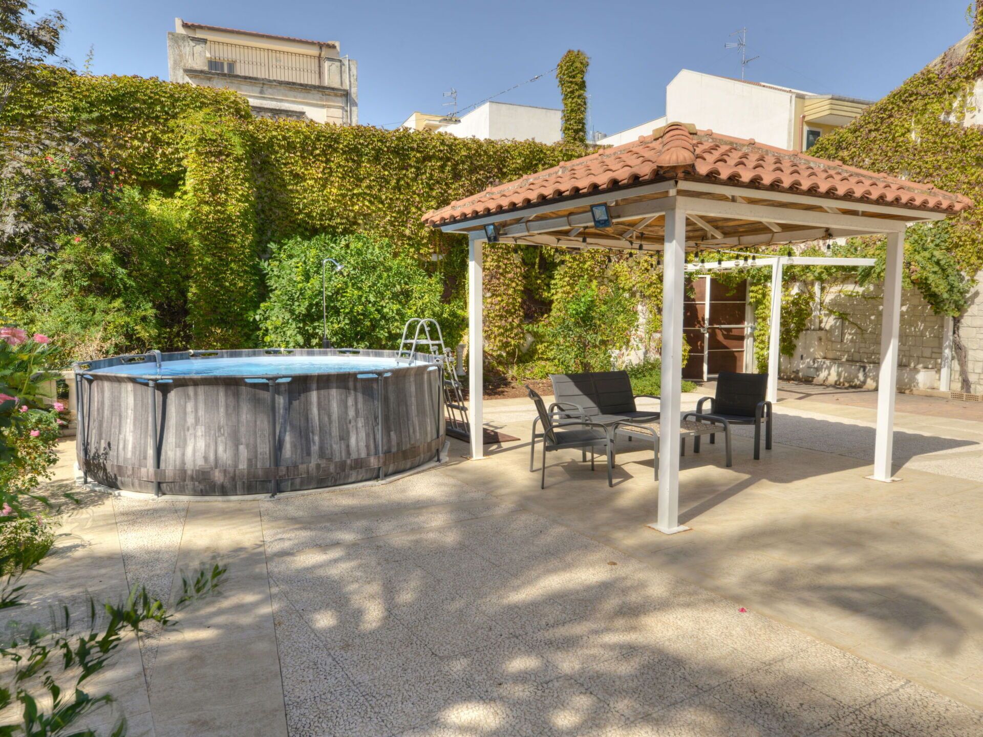 Un jardin avec un jacuzzi, un espace salon extérieur et une pergola.
