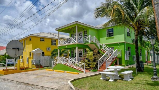 A two-story building with a green and yellow facade, a balcony, and a staircase leading to the upper floor. - Prospect #4 - by Zenbreak (Wanstead)