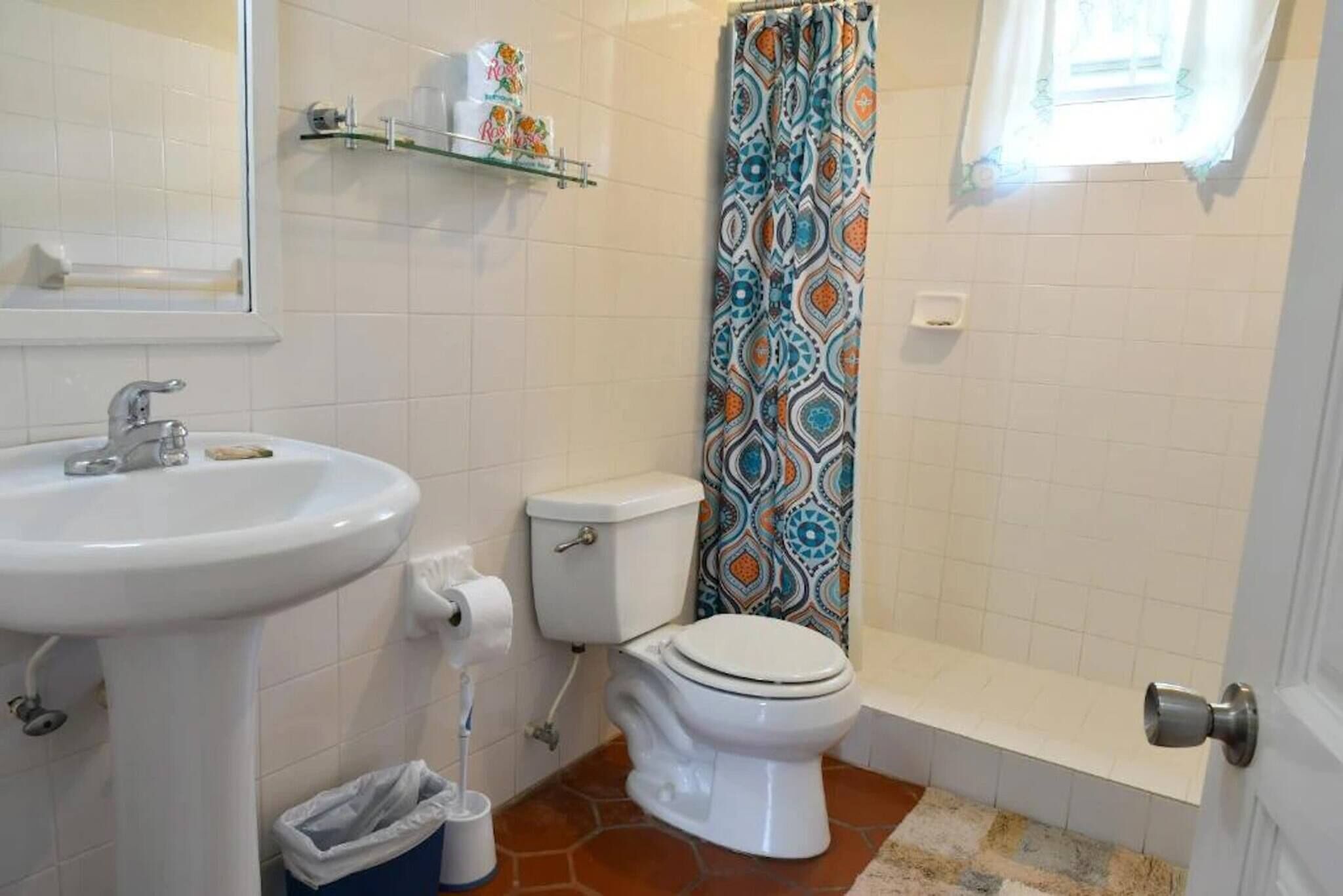 A bathroom with a white sink, toilet, and shower curtain.
