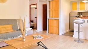 A modern living room with a sofa, a coffee table, and a magazine. There is a kitchen area with cabinets and a refrigerator. - Beautiful apartment for 6 people with WIFI, A/C, terrace, pets allowed and panoramic view (Figareto)