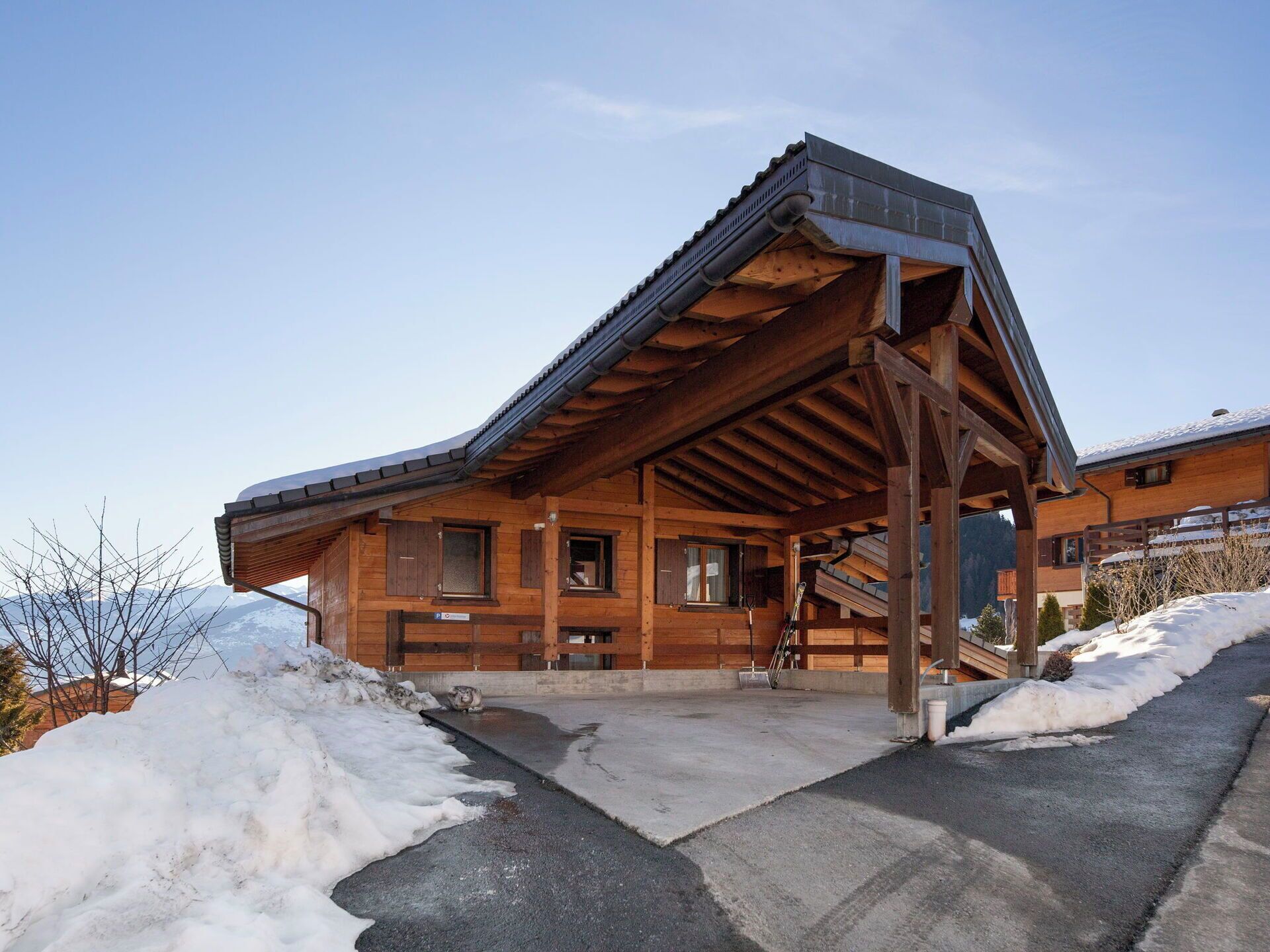 A wooden lodge with a sloped roof, a covered entrance, and a ski lift visible in the background.