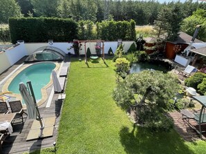 Relax in a serene backyard oasis with a swimming pool, lawn, and pond, perfect for dining or unwinding.