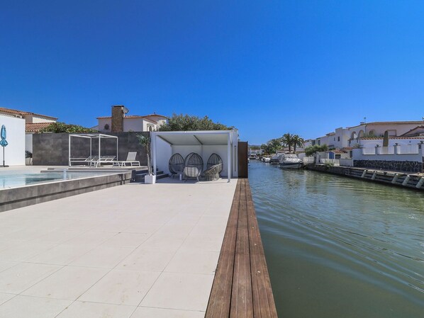 Une propriété située au bord de l’eau, dotée d’une piscine, d’un espace salon et de plusieurs bateaux amarrés à proximité.