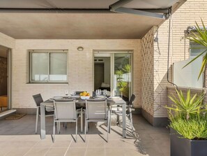A patio with a table set for four, surrounded by chairs, and a potted plant to the right. - Nice apartment for 4 guests with WIFI, A/C, pool, TV, terrace and pets allowed (Torredembarra)