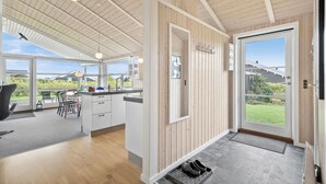 Et moderne køkken med trædetaljer, store vinduer og udsigt til naturen.