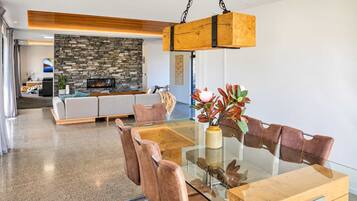 A modern living room with a stone fireplace, a glass dining table, and leather chairs.
