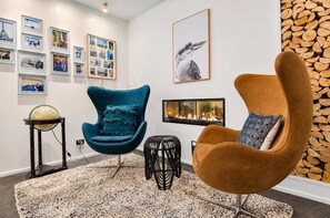 A modern living room with a blue armchair, a brown armchair, a globe on a stand, and a fireplace.