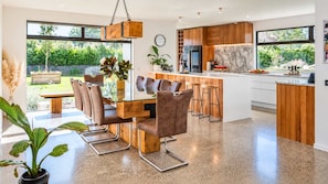 Una cocina moderna con armarios de madera, salpicadero de mármol y una isla grande con taburetes de bar.