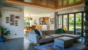 A modern living room with a sectional sofa, a dining area, and a kitchen. - Luxury 5BR Home • Sauna • Hot Tub • Parking (Prebbleton)