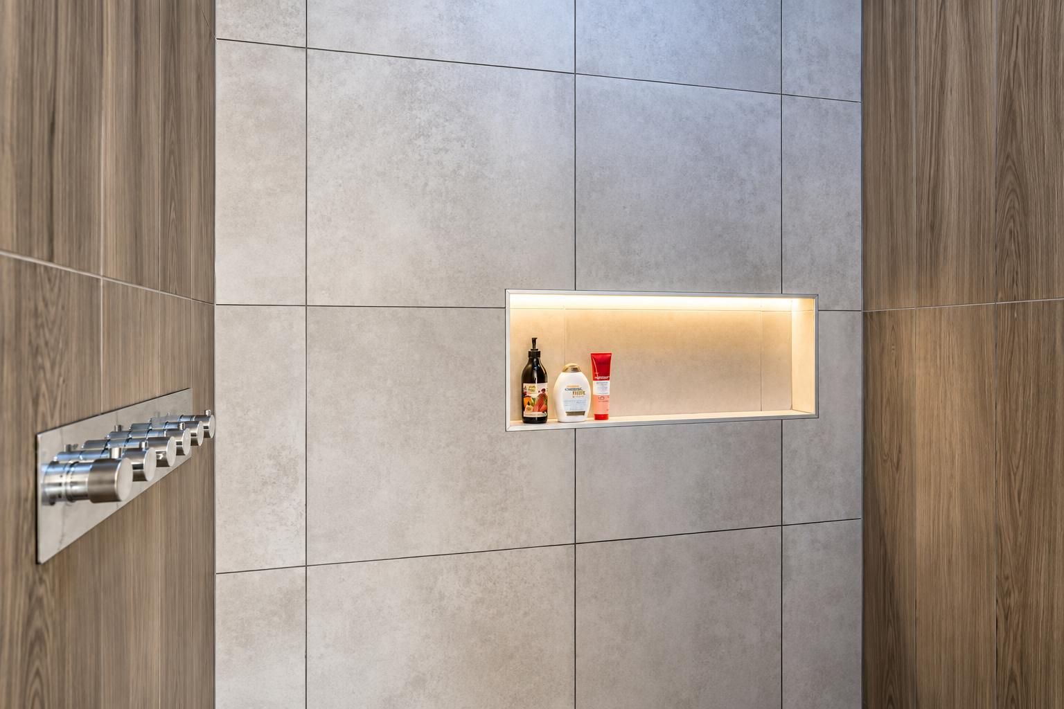 A bathroom with a built-in shelf holding toiletries, a towel rack, and a mirror.