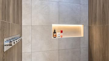 A bathroom with a built-in shelf holding toiletries, a towel rack, and a mirror.