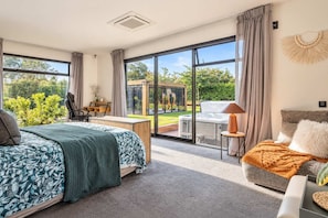 Un dormitorio moderno con una cama grande, un escritorio y vistas a un jacuzzi y jardín.
