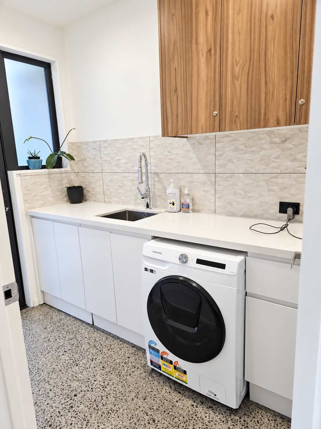 Cocina compacta con lavadora integrada, un lavabo y un mueble de madera en la parte superior.