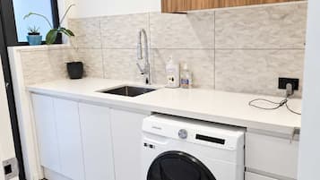 Cocina compacta con lavadora integrada, un lavabo y un mueble de madera en la parte superior.