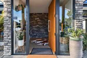 A modern entrance with a stone wall, wooden door, and a welcome mat.