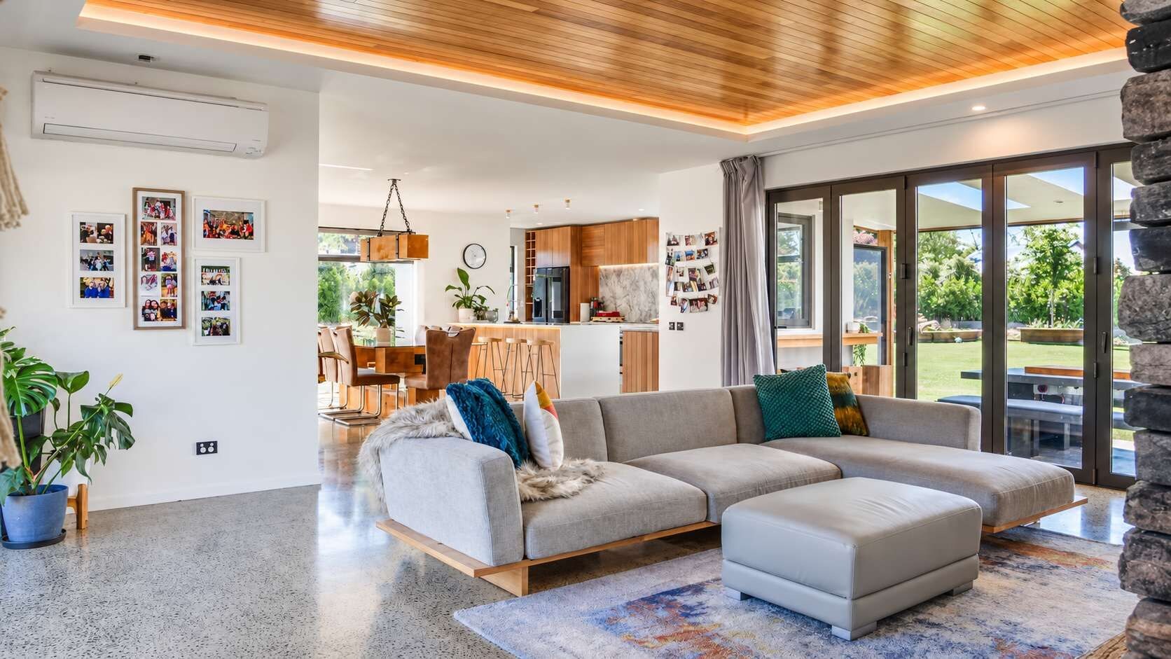 En moderne stue med en hjørnesofa, spiseplads og et køkken.