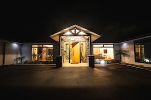 A modern building with a stone facade, a central entrance with a wooden door, and two large planters on either side.