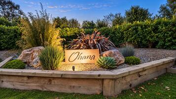 Un jardín ajardinado con un letrero de madera que dice 'Ohana'.