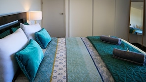 Une chambre d’hôtel avec un lit, des oreillers, une lampe de chevet et un miroir.