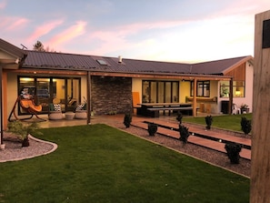 A modern house with a stone facade, a covered patio, and a well-maintained lawn.