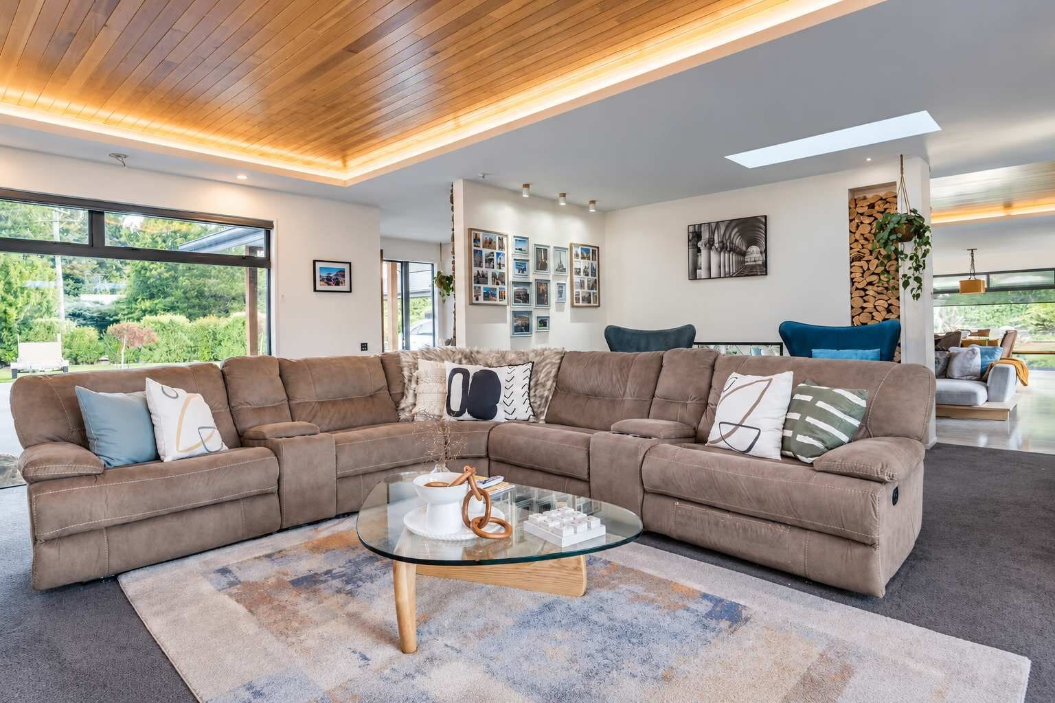 A modern living room with a sectional sofa, a glass coffee table, and a large window providing a view of the outdoors.