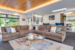 A modern living room with a sectional sofa, a glass coffee table, and a large window providing a view of the outdoors.
