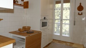 A kitchen with white cabinets, a wooden countertop, a built-in oven, and a double door leading outside. - Nice apartment for 5 guests with WIFI, TV and balcony (Bordighera)