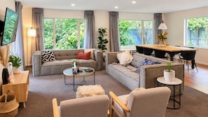 Un salon moderne comprenant un canapé, des fauteuils, une table basse et un coin repas avec une table et des chaises.