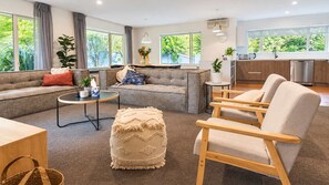 A modern living room with a sofa, chairs, a coffee table, and a kitchen area visible through an open door.