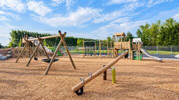 A playground with swings, a seesaw, and a climbing structure.