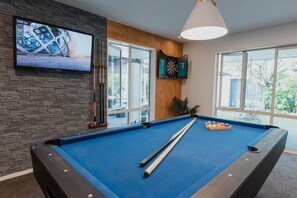 A pool table with a dartboard and a television mounted on a stone wall. - Hidden Gem of Christchurch - Sleeps 12 (Christchurch)