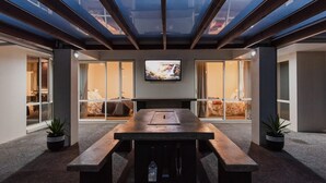 A modern conference room with a long table, comfortable seating, and a large TV screen.