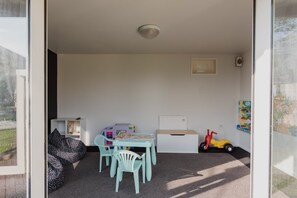 A room with a table and chairs, a bookshelf, a toy car, and a bean bag. - Hidden Gem of Christchurch - Sleeps 12 (Christchurch)