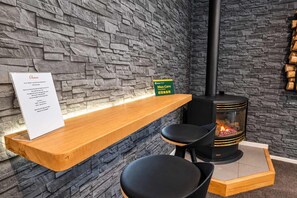 A stone wall interior with a wooden bench, a sign, and a wood-burning stove.