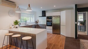 A modern kitchen with a central island, stainless steel appliances, and bar stools.