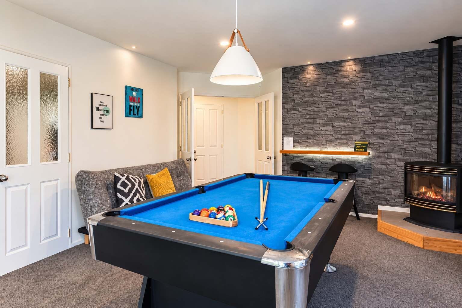A pool table with balls, a sofa, a fireplace, and a wall with a textured pattern.