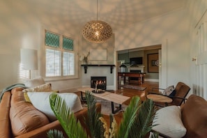 A living room with a fireplace, a sofa, a coffee table, and a hanging light fixture.