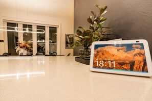 A tablet displaying the time and date, a plant, and a reception area with a glass door and chairs.