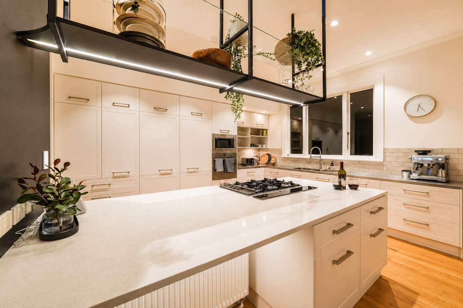 Een moderne keuken met een centraal eiland, inbouwapparatuur en een hangende plant.