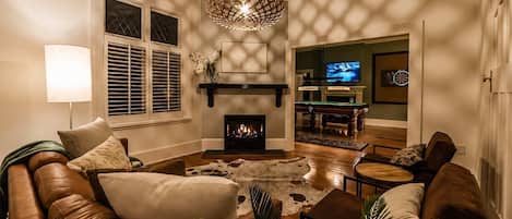 Una sala de estar con chimenea, sofá de cuero y televisor.