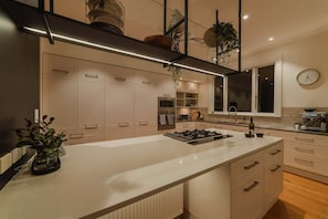 Et moderne køkken med en central ø, indbyggede apparater og et minimalistisk design.