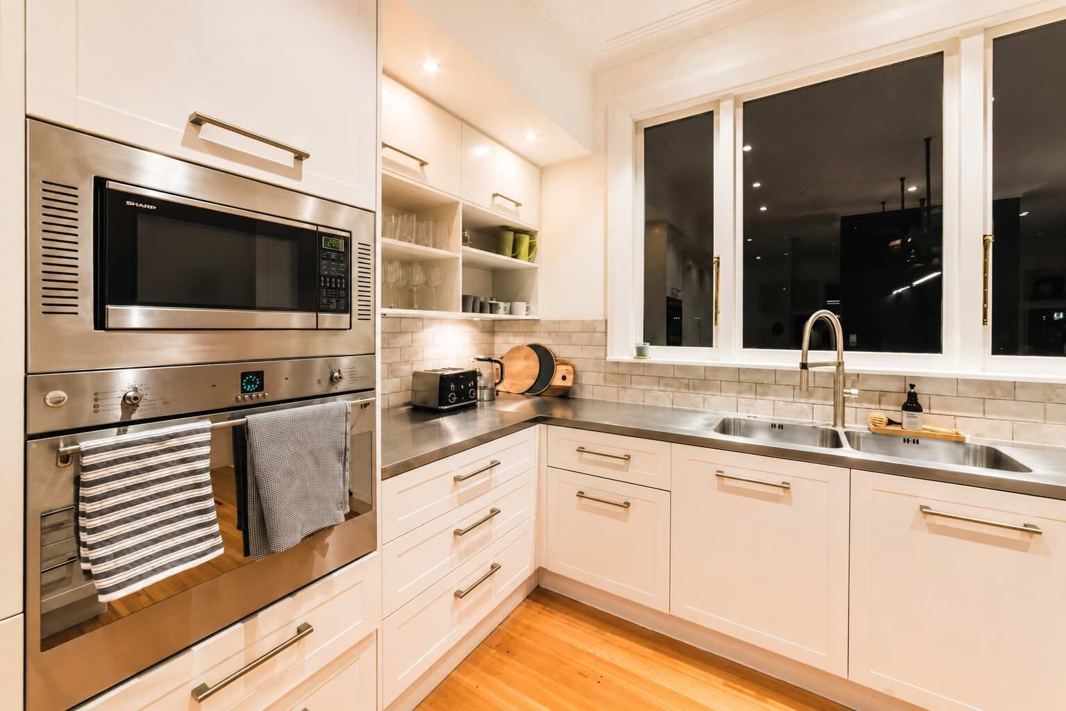 A modern kitchen with stainless steel appliances, a window with a view, and a wooden countertop.