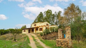 Une maison à deux étages, avec un pilier en pierre et un chemin de gravier menant à l’entrée.