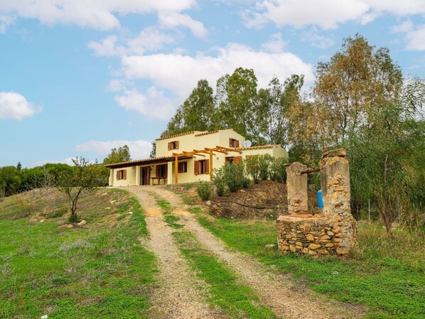 Una casa de dos pisos con un pilar de piedra y un camino de grava que lleva a la entrada.