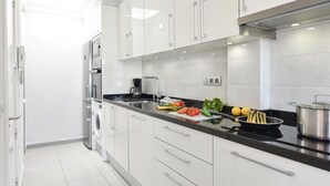 Cocina moderna con armarios blancos, electrodomésticos de acero inoxidable y encimera negra.