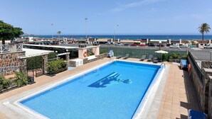 Una piscina con vistas al océano y un estacionamiento al fondo.
