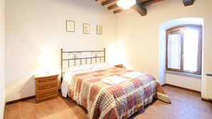 Une chambre à coucher avec un lit, une table de chevet, une commode et une fenêtre avec des rideaux.