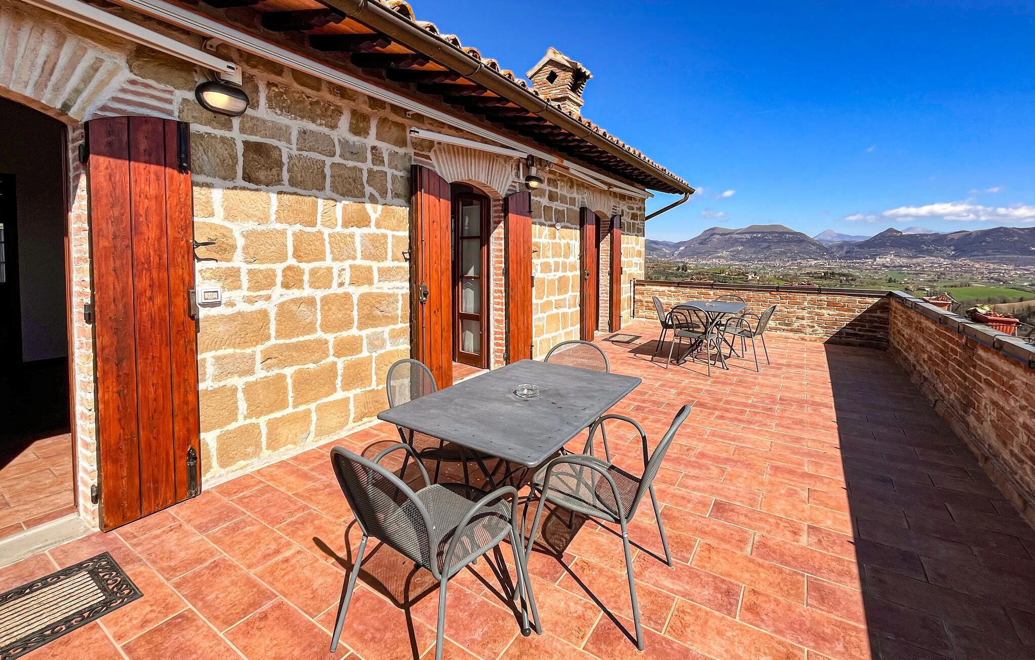 A stone building with a patio, a table, and chairs.