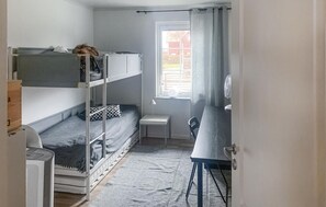 Cozy dormitory room with bunk beds, desk area, and a window offering a view of the outside.